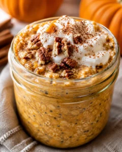 Creamy pumpkin overnight oats topped with whipped cream and chopped nuts