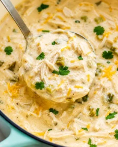 Macro view of creamy keto white chicken chili showing thick texture, cheese strands and parsley leaves