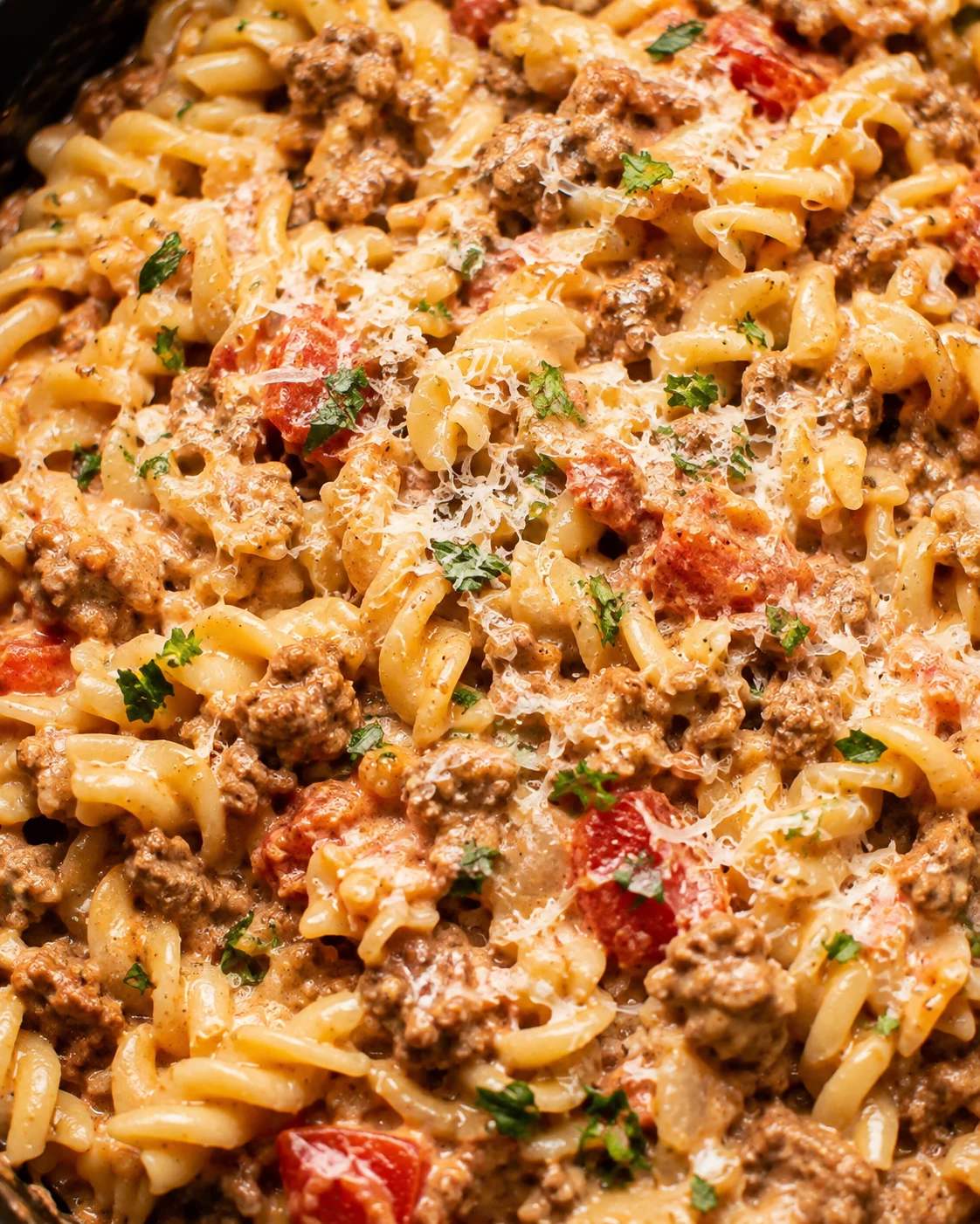 Close-up of creamy ground beef pasta with tomatoes, cheese, and herbs