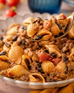 Spoon lifting a bite of easy healthy taco pasta with shell pasta, black beans, ground beef and creamy sauce