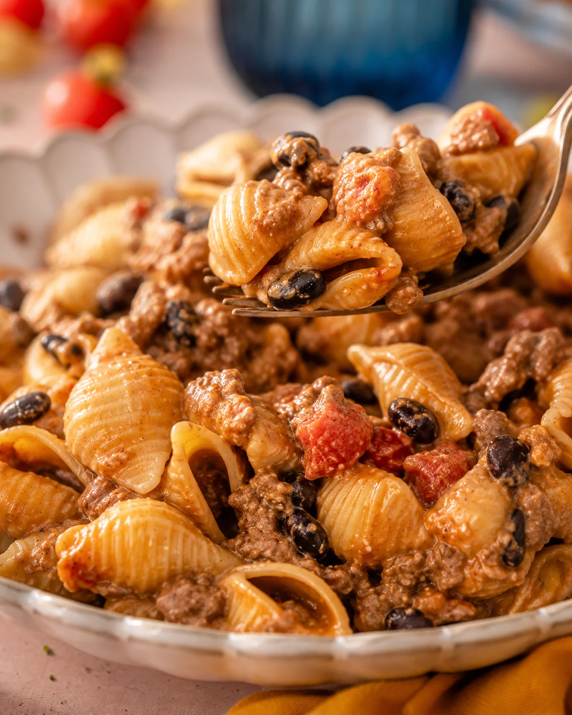 Spoon lifting a bite of easy healthy taco pasta with shell pasta, black beans, ground beef and creamy sauce