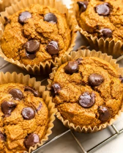 Close-up of pumpkin chocolate chip protein muffins in paper liners with visible chocolate chips