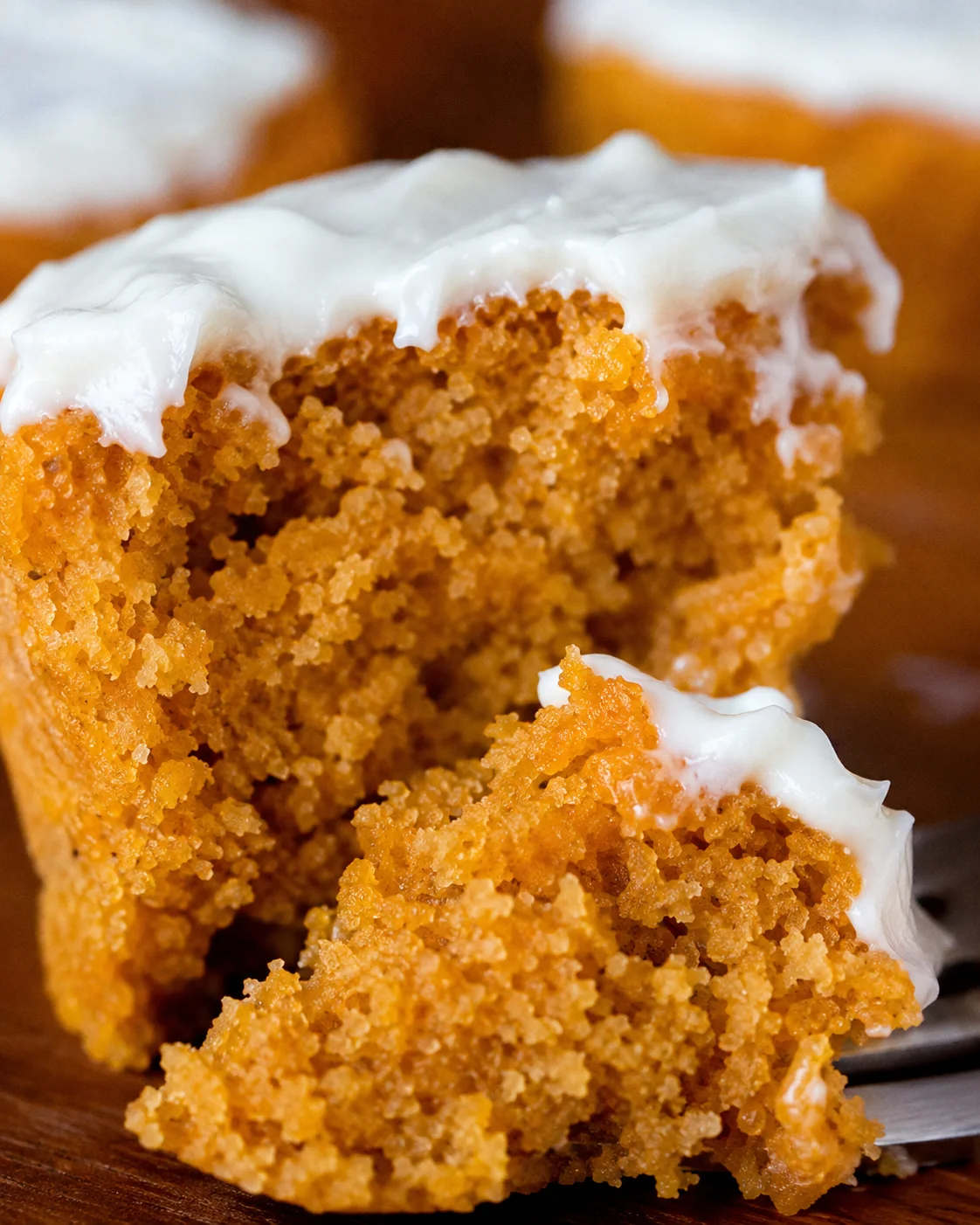 Close-up detail of a bitten flourless pumpkin muffin crumb with frosting and a forkful piece