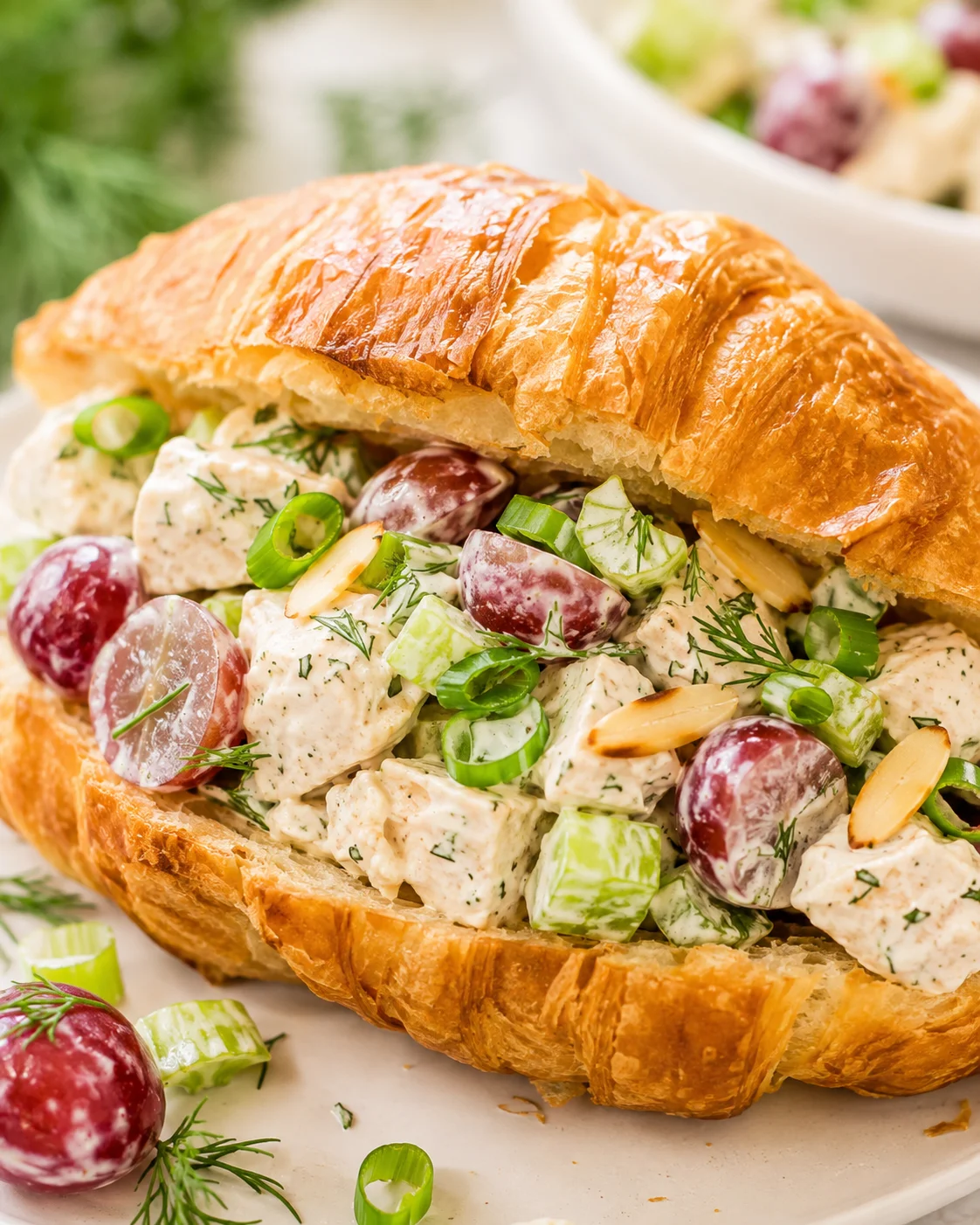 Greek yogurt chicken salad piled into a flaky croissant with grapes and celery