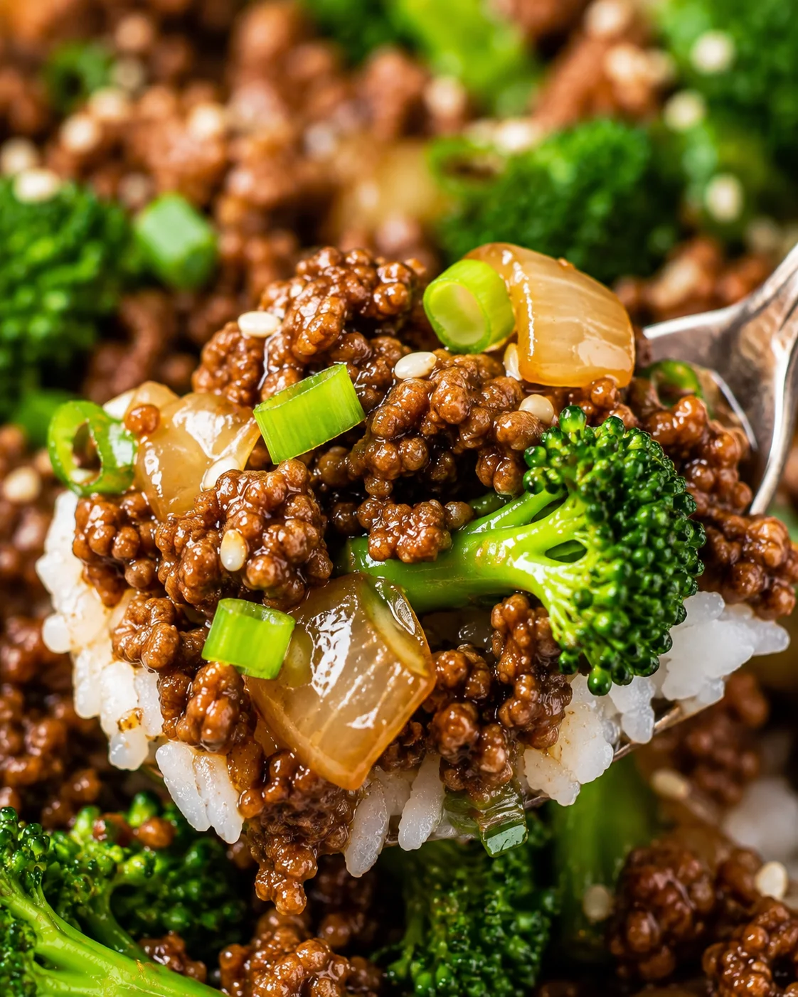 Close-up detail of a forkful showing the texture of ground beef, broccoli and onions