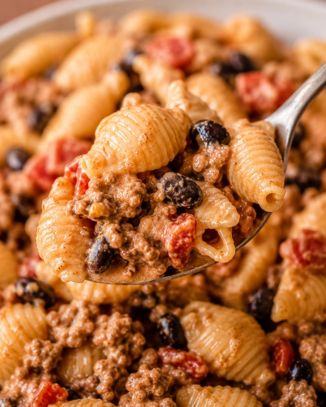 Spoonful of Healthy Taco Pasta showing pasta shells, black beans, ground beef and diced tomatoes