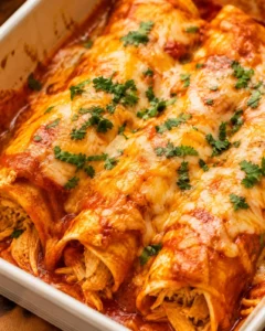 Baked high protein chicken enchiladas in a casserole dish with melted cheese and cilantro