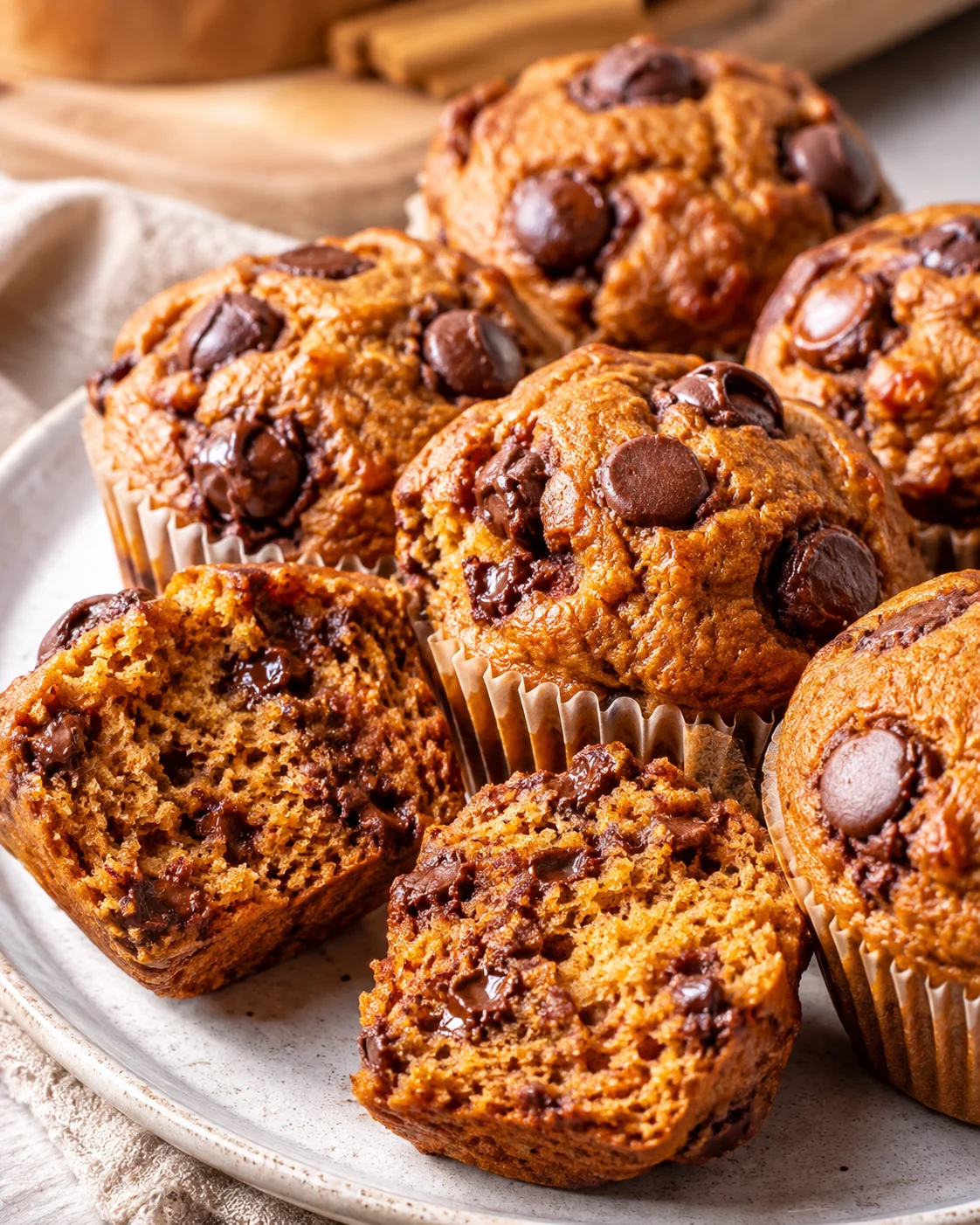 Plate of high protein pumpkin cottage cheese muffins with chocolate chips, one cut in half to show interior