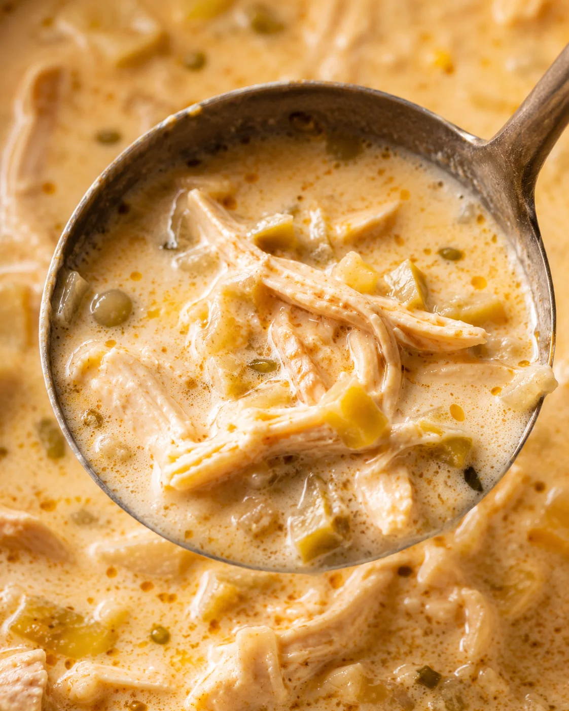 Ladle scooping creamy keto white chicken chili showing shredded chicken and diced green chiles