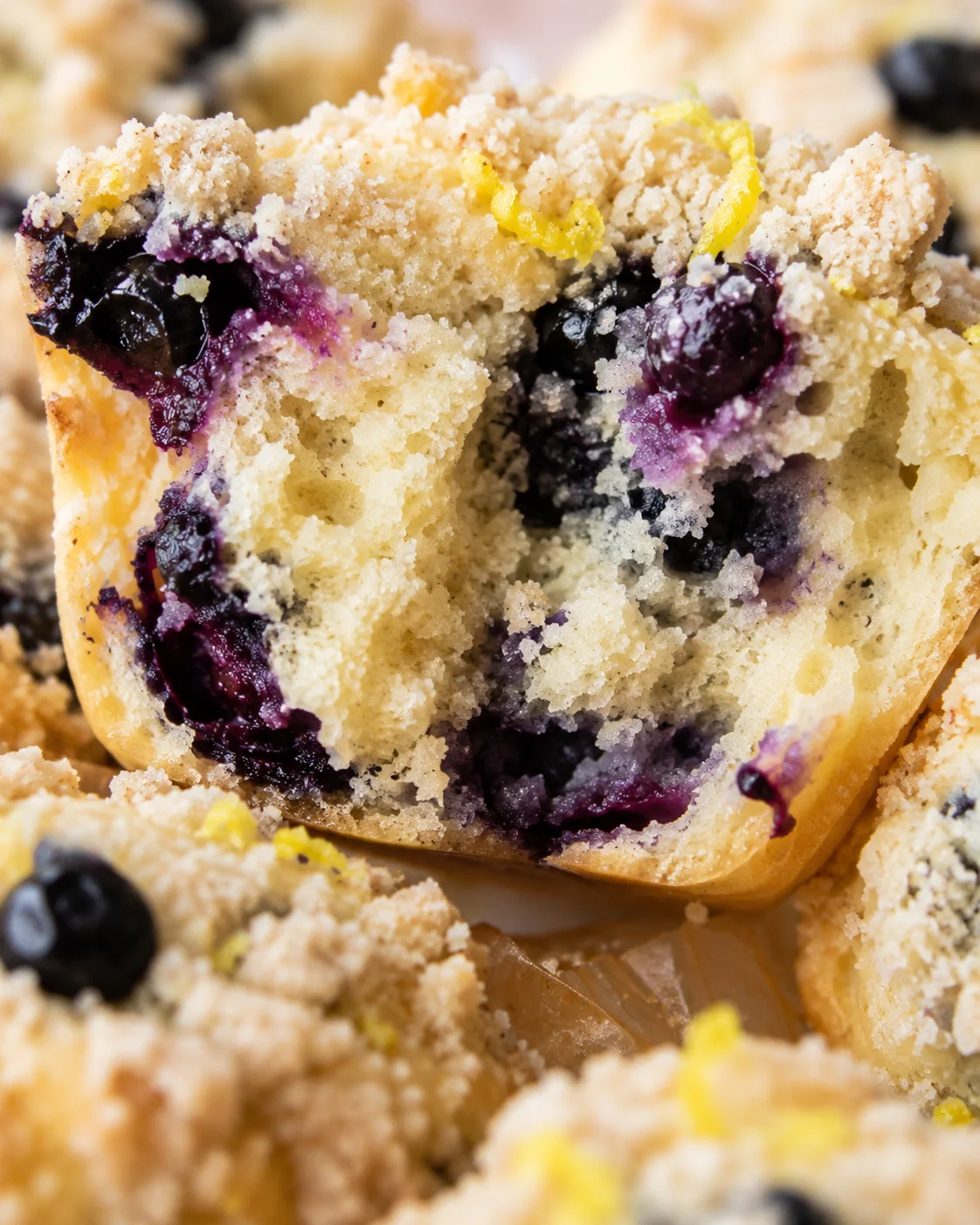 Macro view of the interior crumb of a lemon blueberry muffin showing blueberries, moist crumb, and streusel