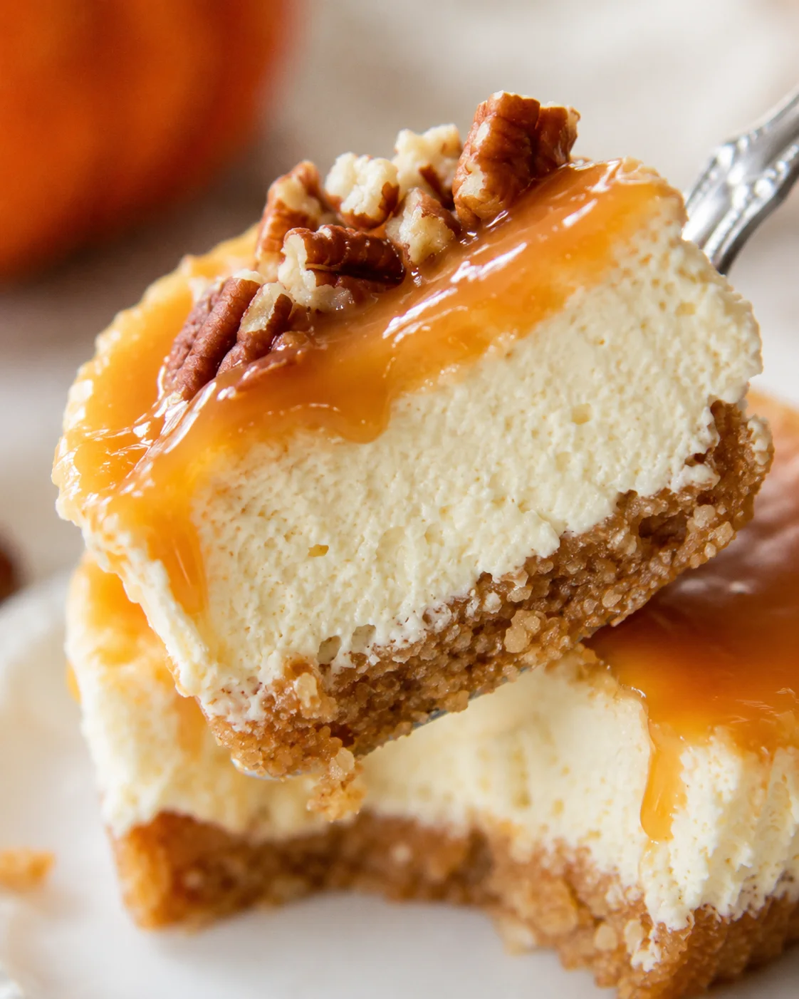 Close-up forkful of mini keto pumpkin cheesecake showing creamy interior and crumb crust with caramel and pecans