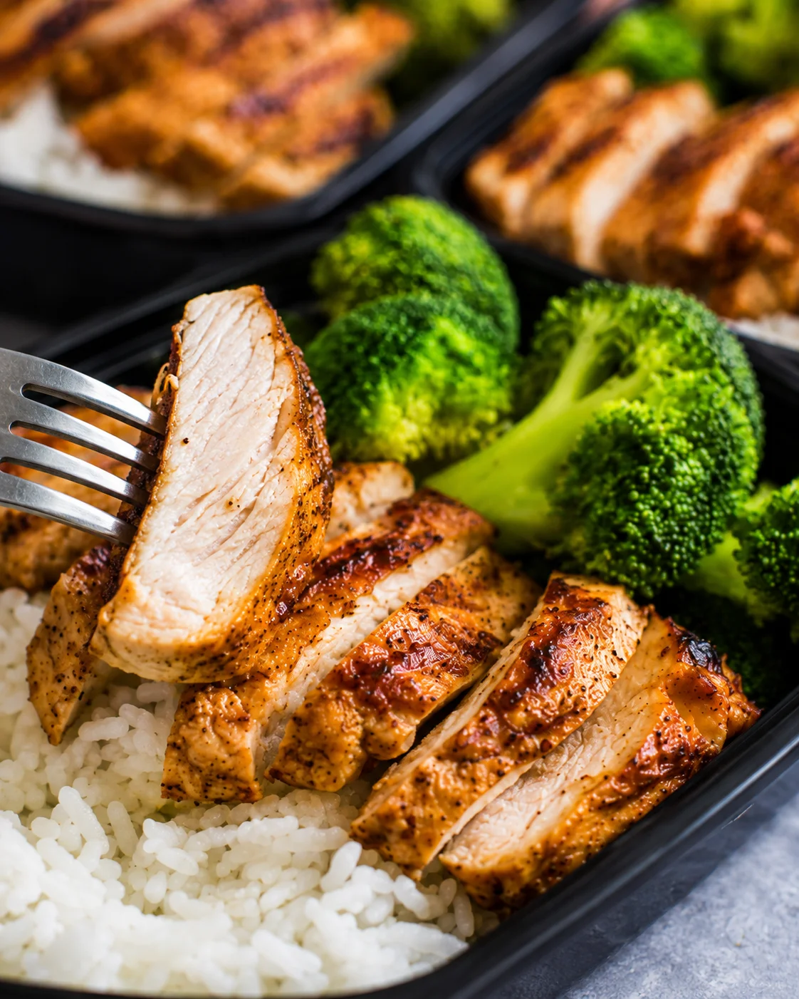 Sliced seasoned chicken with steamed broccoli and rice in meal prep containers