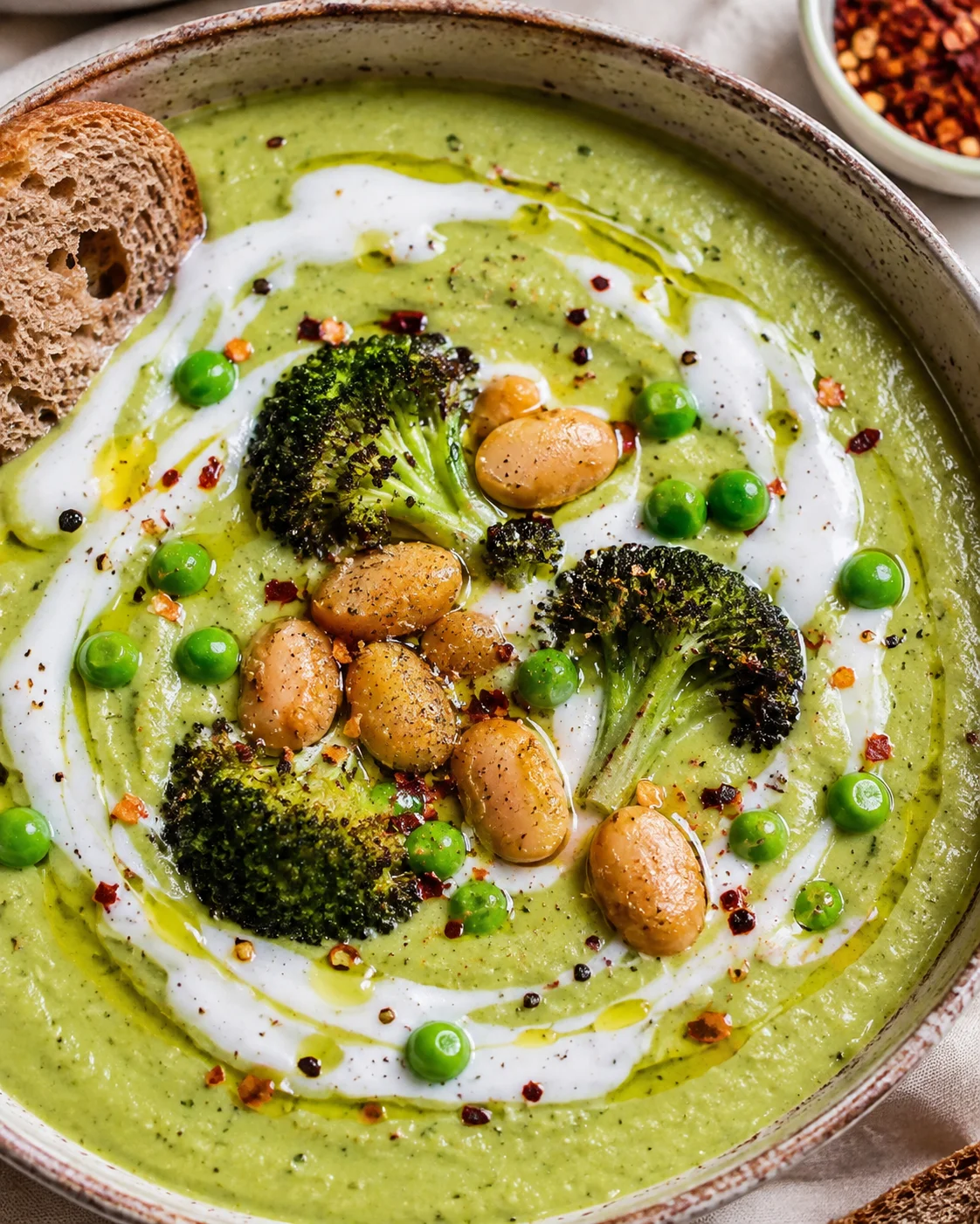 Creamy green vegetable and bean soup with topping and bread