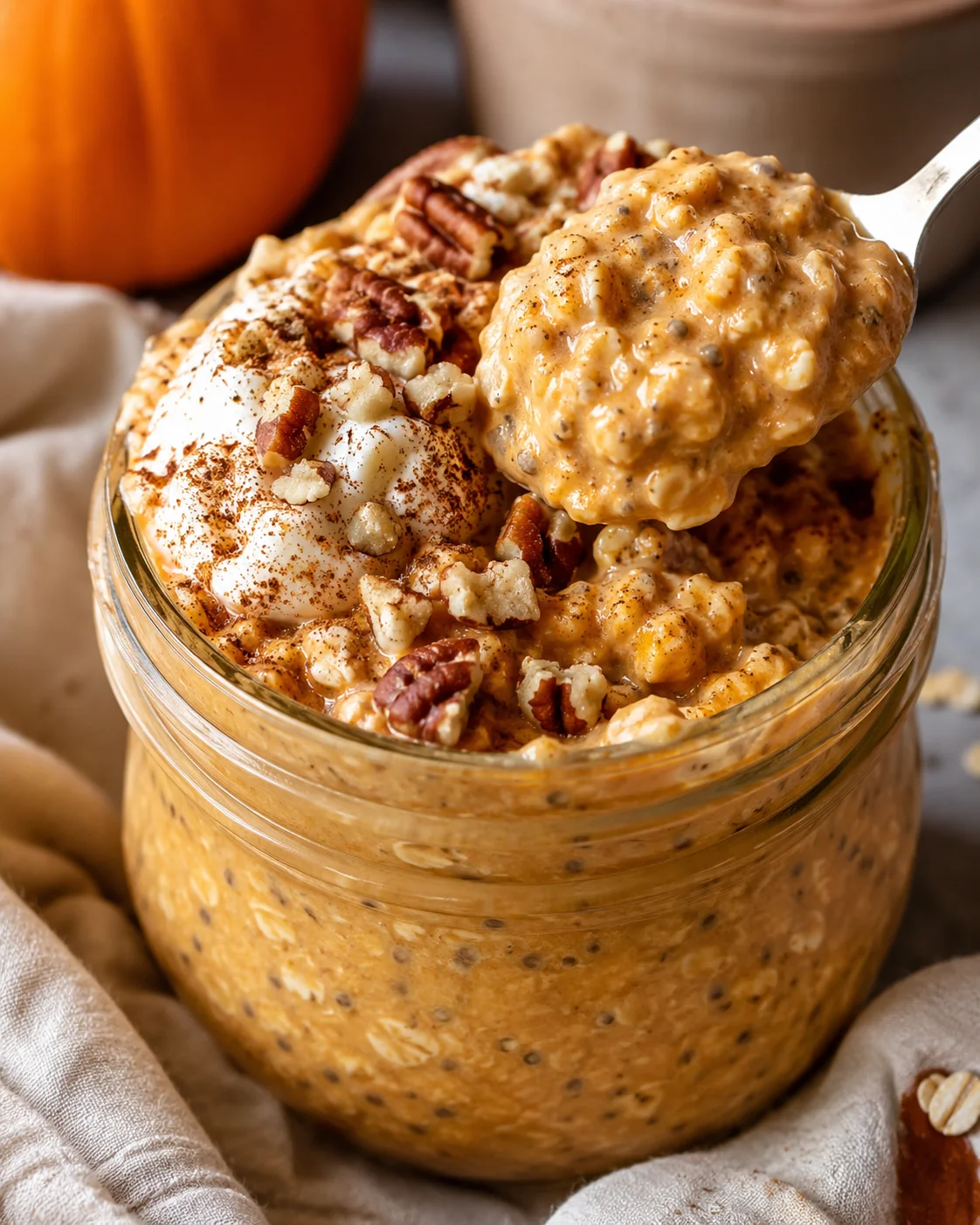 Creamy pumpkin overnight oats topped with nuts and spices in a glass jar.
