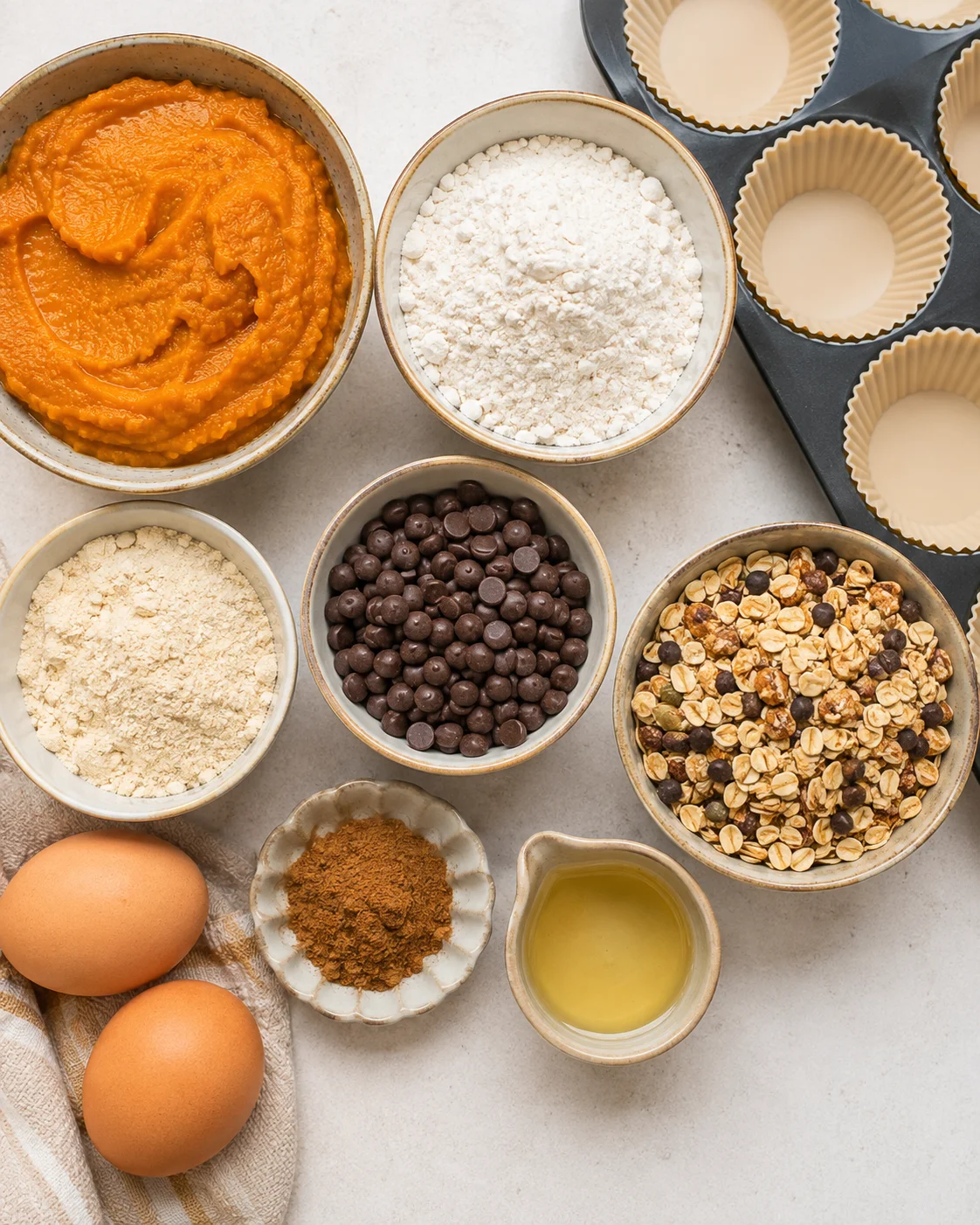 Ingredients for protein pumpkin muffins including pumpkin puree, eggs, and chocolate chips.