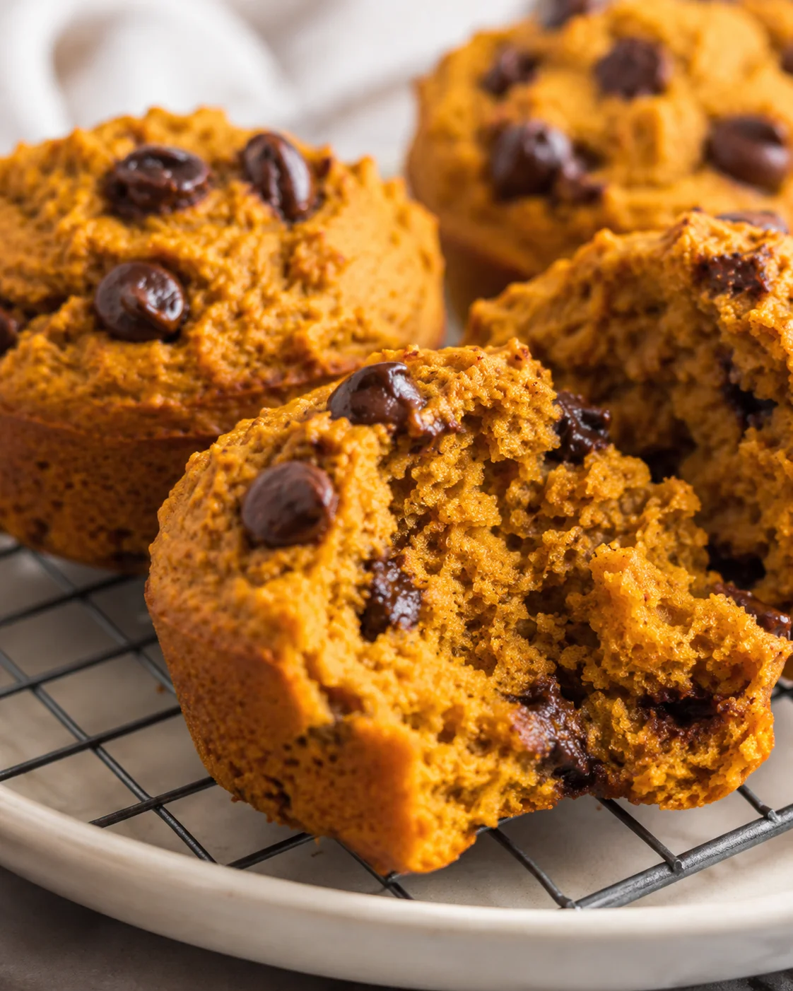 close-up of golden pumpkin muffins with dark chocolate chips on a cooling rack