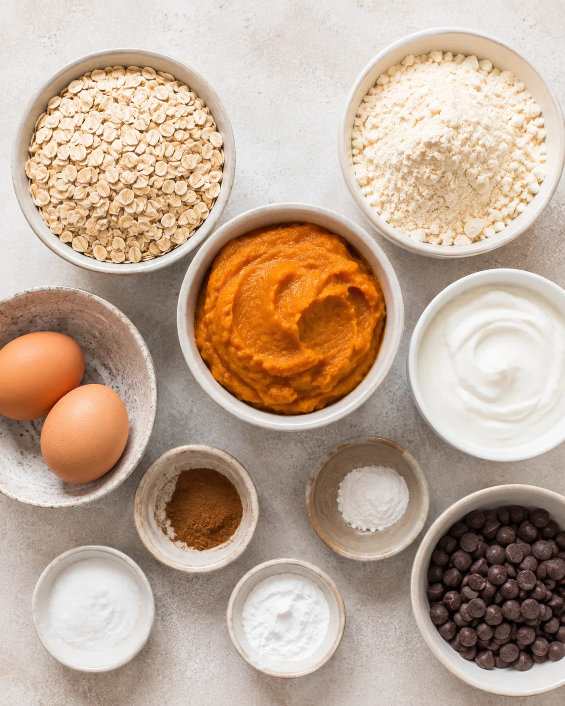 Ingredients for pumpkin protein muffins including oats, yogurt, pumpkin, and chocolate chips.