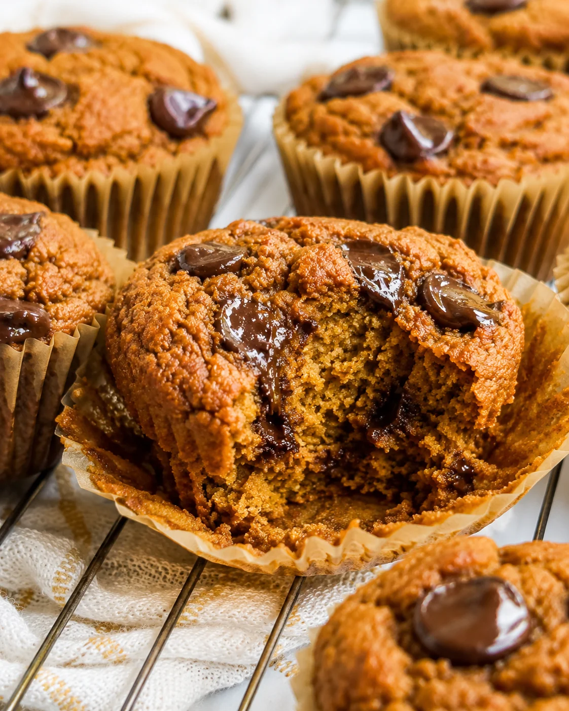close-up of golden-brown muffins with crumb topping and melted chocolate chips on a cooling rack