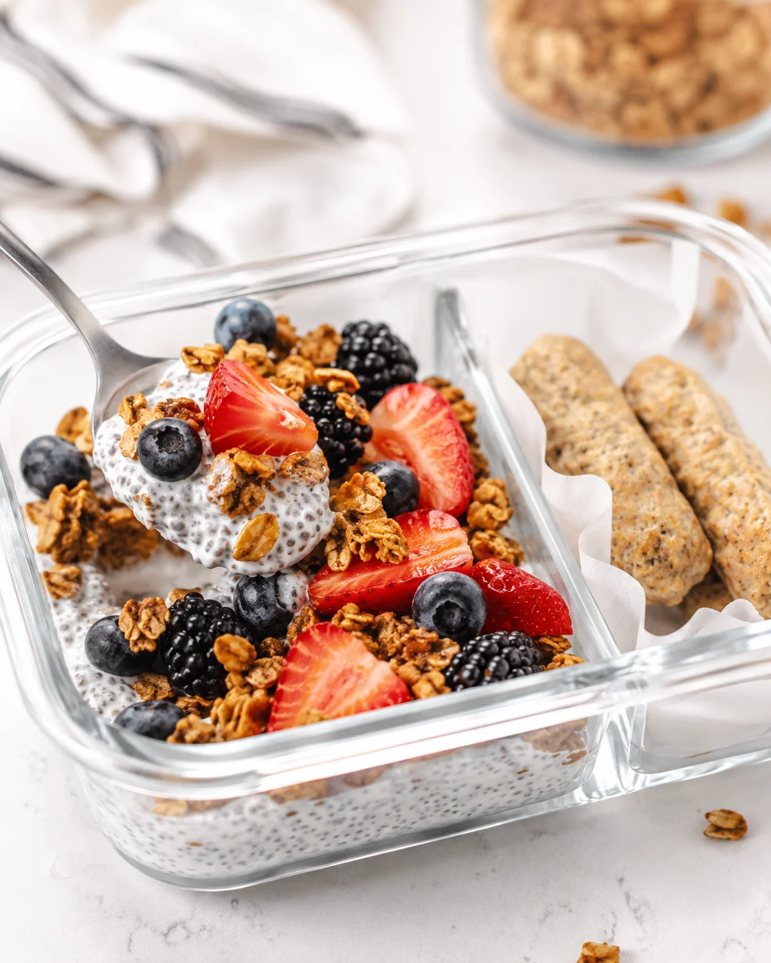 glass container of chia pudding topped with granola and fresh berries