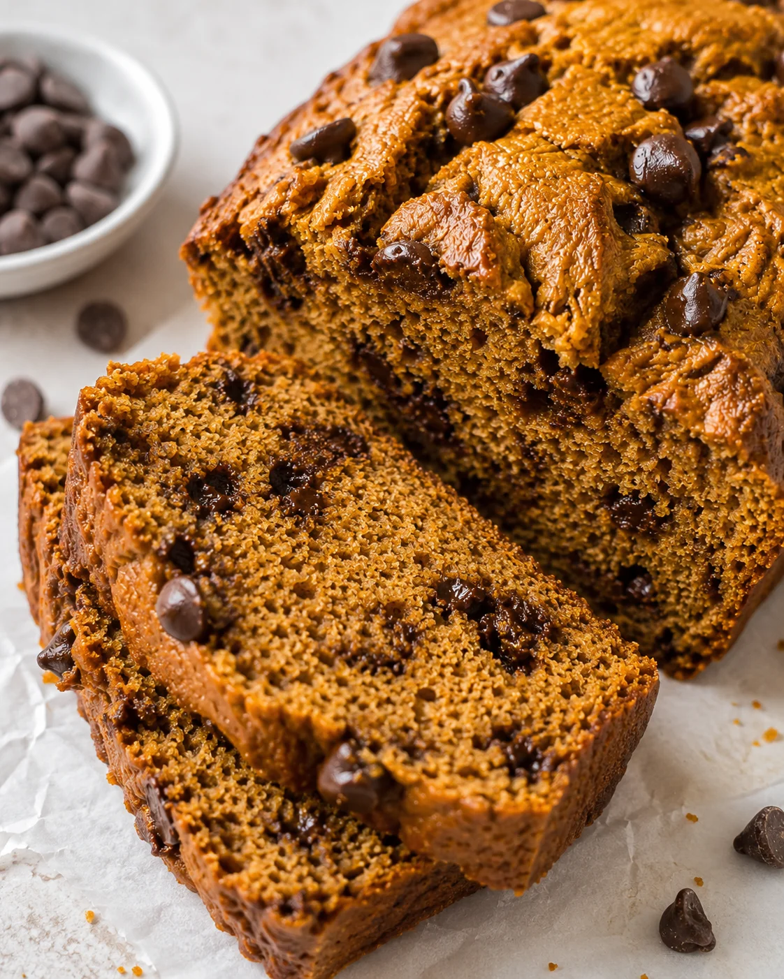 Moist banana bread with chocolate chips, sliced to reveal a dense, golden crumb.
