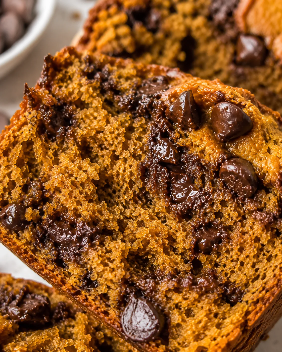 close-up of a moist chocolate-chip loaf slice with glossy melted chocolate chips