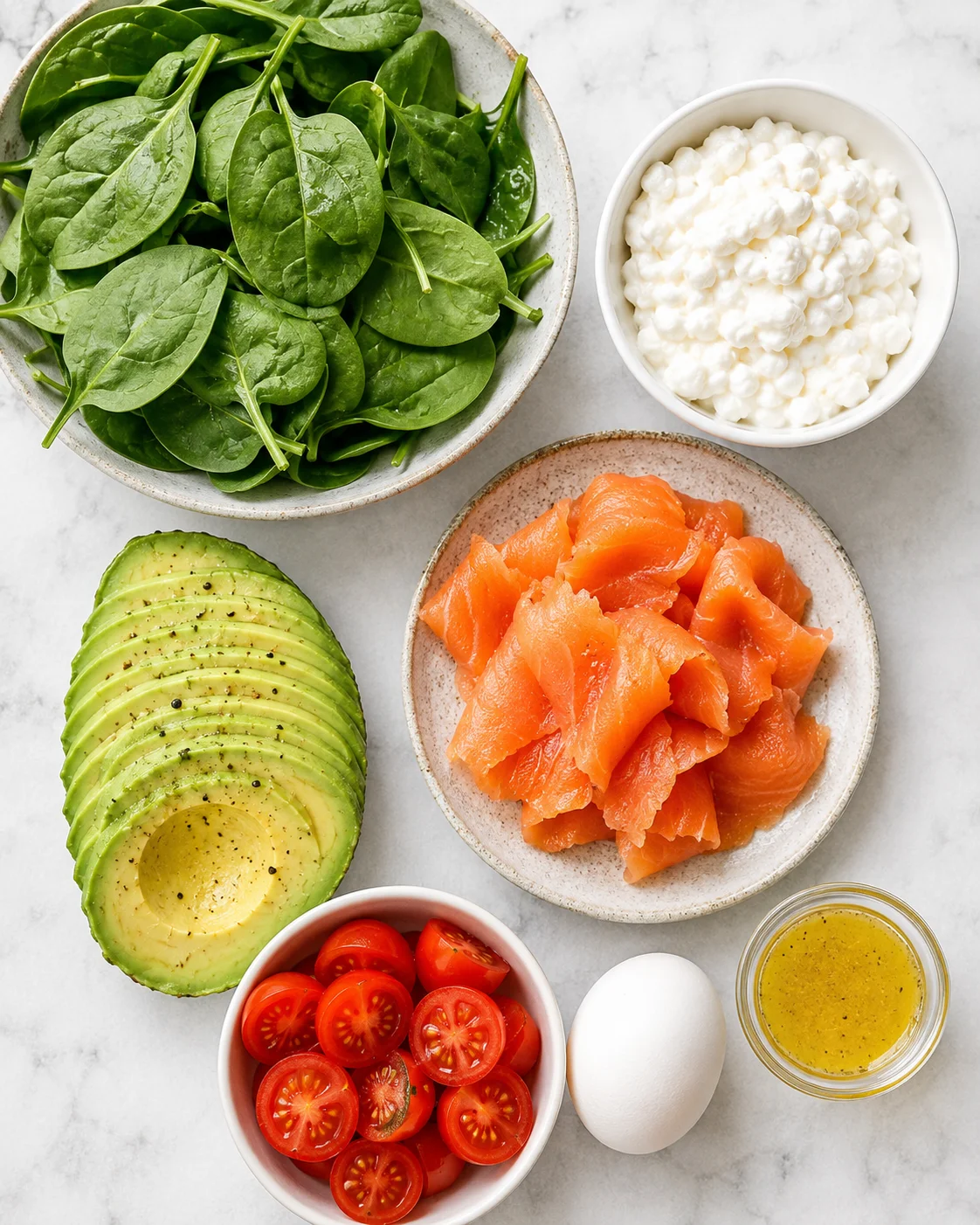 Assorted fresh ingredients for a healthy protein breakfast bowl, including spinach, salmon, and avocado