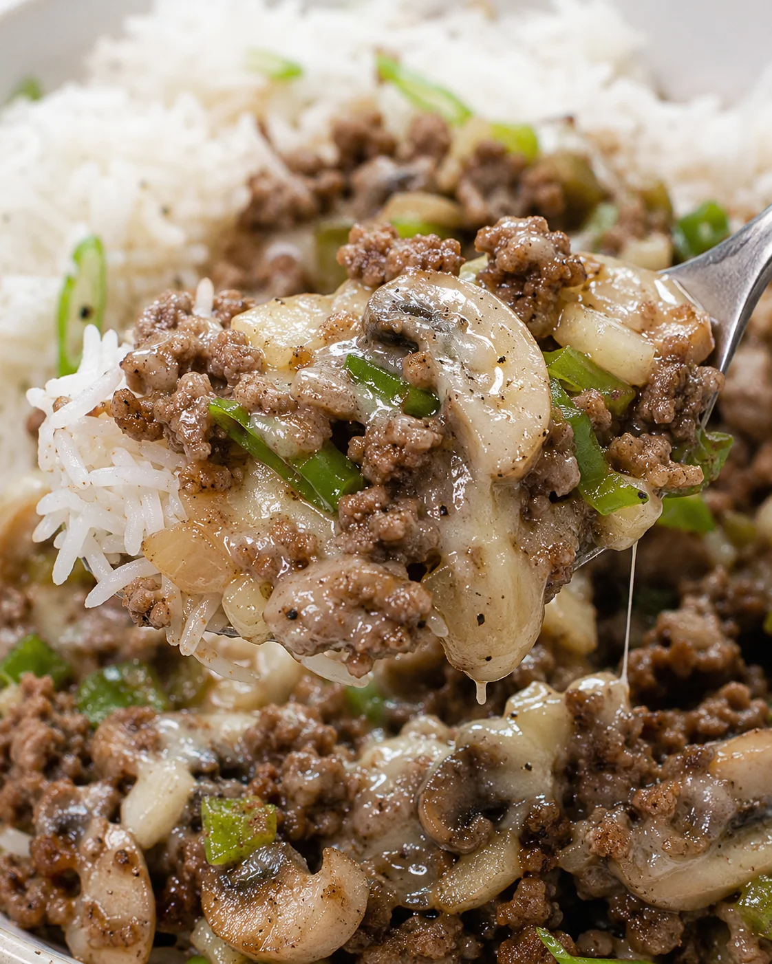 Spoonful detail of Philly cheesesteak meal prep showing mushroom slice, ground beef and rice