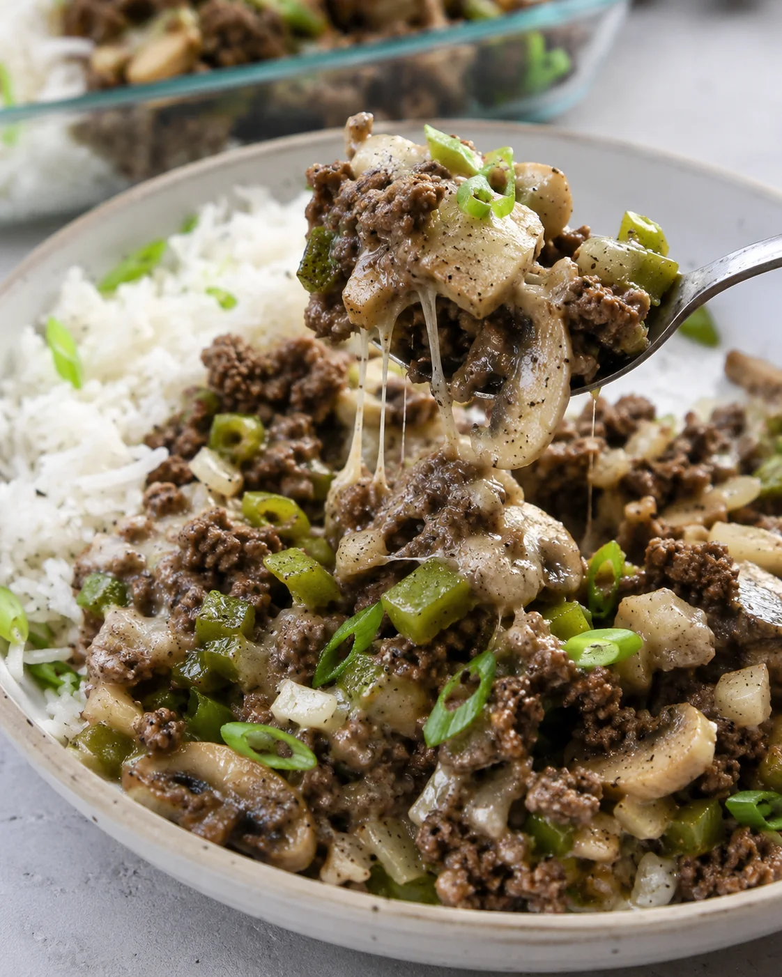 Philly cheesesteak meal prep bowl with rice and a fork lifting a cheesy bite