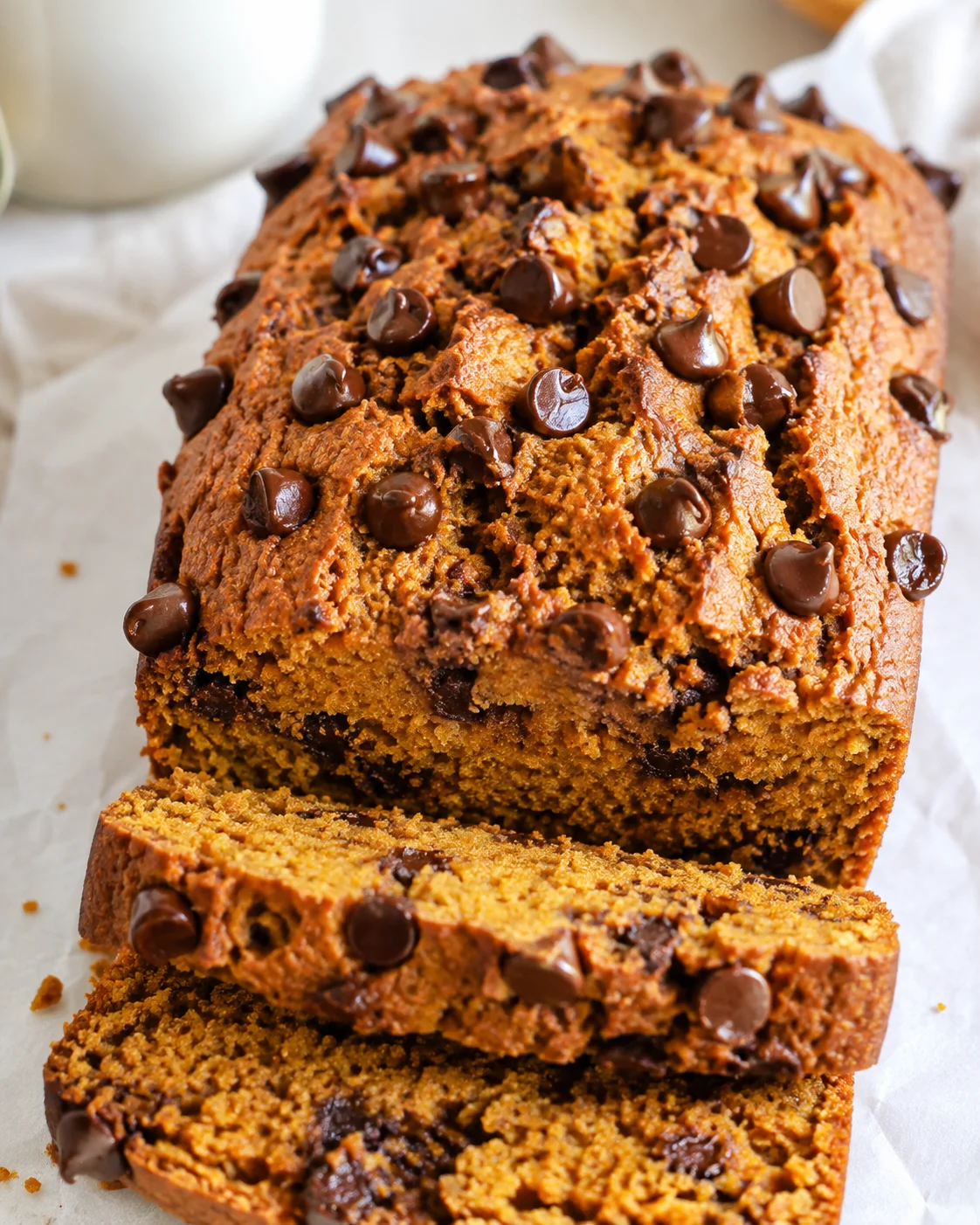 Protein pumpkin bread loaf topped with chocolate chips, two slices cut from the front