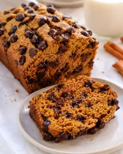 Protein pumpkin bread loaf with a sliced piece on a plate and a glass of milk