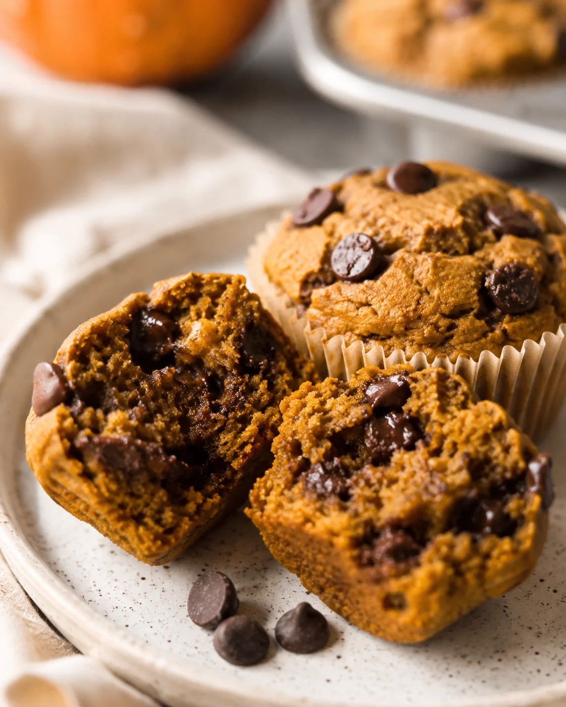 Plated pumpkin protein muffin with a split open muffin showing gooey chocolate chips
