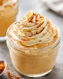 Close-up of pumpkin spice whipped Greek yogurt in a glass jar topped with piped cream and cinnamon