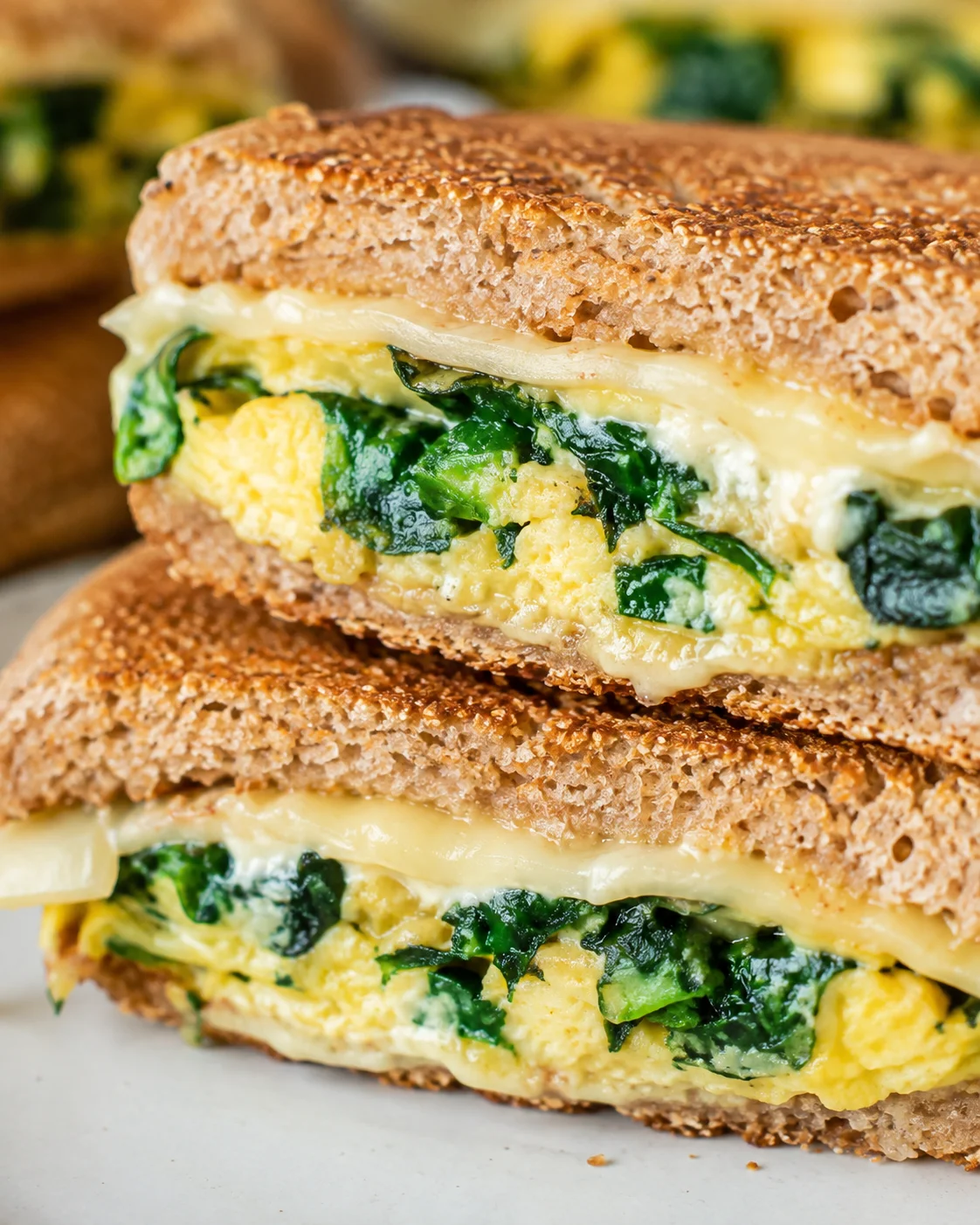 Close-up of the inside of a spinach and egg sandwich showing egg, wilted spinach and melted cheese