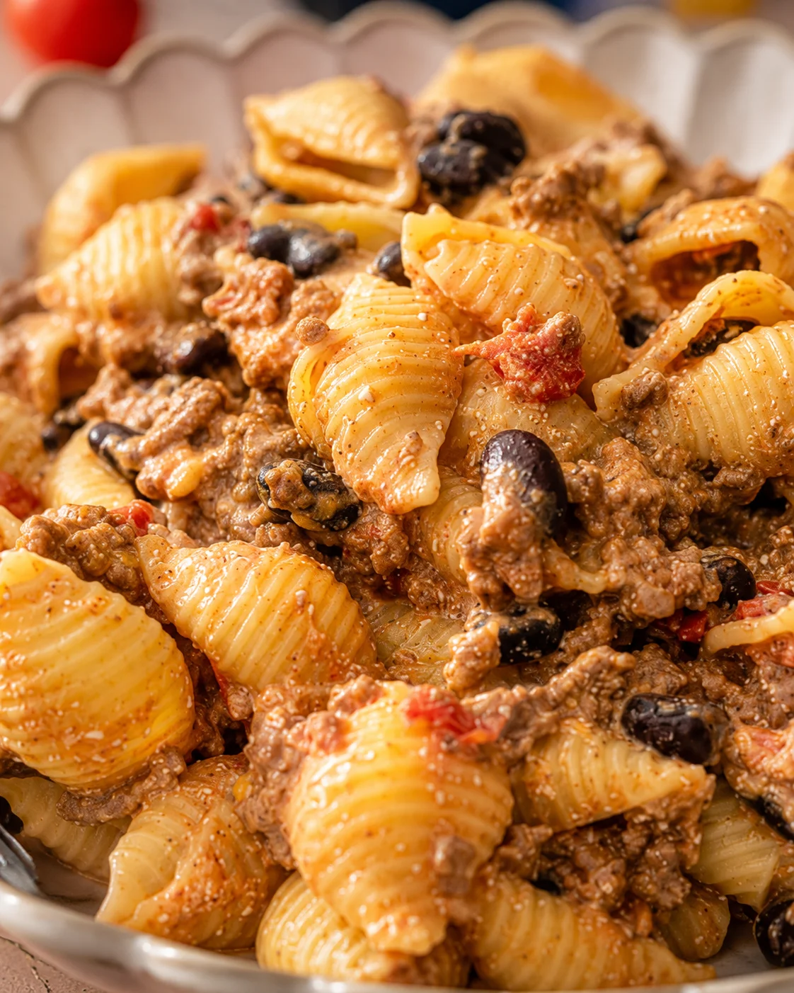 Tight detail of easy healthy taco pasta showing creamy sauce coating shells, beans and ground beef